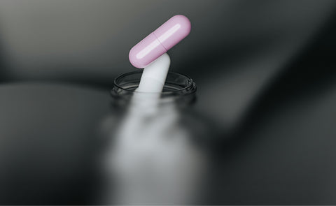 Pink pill & White pill coming out of a bottle